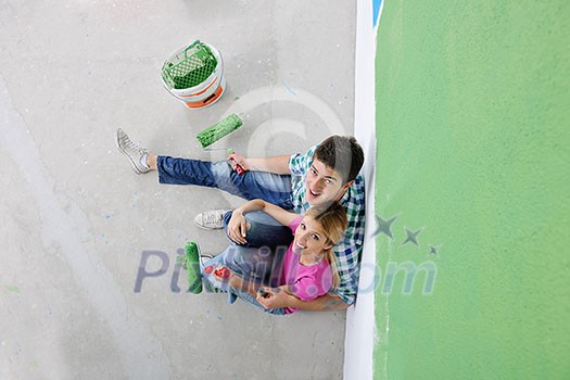 happy young couple relax after painting white wall in green and blue color in their new home happy young couple relax after painting white wall in green and blue color in their new home