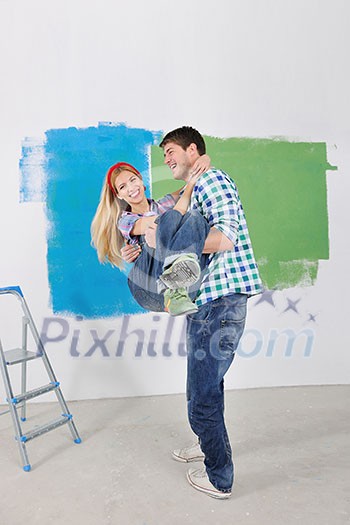 happy young couple paint in green and blue color white wall of their new home happy young couple paint in green and blue color white wall of their new home