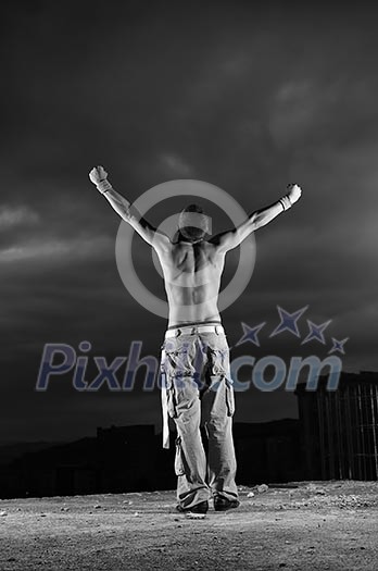 Man with his arms wide open outdoor against dark sky Man with his arms wide open outdoor against dark sky