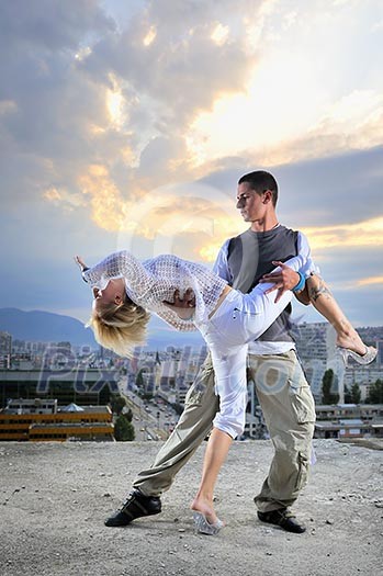 romantic urban couple dancing on top of the bulding