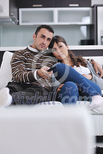 Relaxed young couple watching tv at home in bright living room Relaxed young couple watching tv at home in bright living room