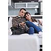 Relaxed young  couple watching tv at home in bright living room