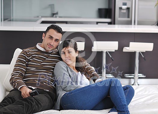 Relaxed young couple watching tv at home in bright living room Relaxed young couple watching tv at home in bright living room