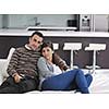 Relaxed young  couple watching tv at home in bright living room
