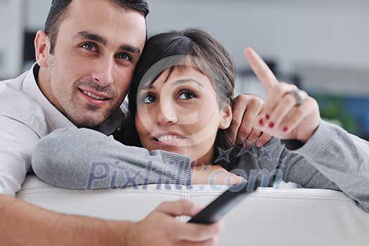 Relaxed young couple watching tv at home in bright living room Relaxed young couple watching tv at home in bright living room