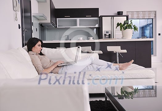 relaxed young woman working on laptop computer in bright home indoor relaxed young woman working on laptop computer in bright home indoor