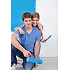 happy young couple paint in green and blue color white wall of their new home