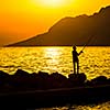 Fisherman silhouette on the beach at colorful sunset