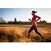 Young woman running outdoors on a lovely sunny winter/fall day (motion blurred image)