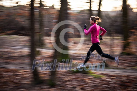 Young woman running outdoors in a city park on a cold fall/winter day (motion blurred image) Young woman running outdoors in a city park on a cold fall/winter day (motion blurred image)