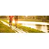 Couple running outdoors, at sunset, by a river, staying active and fit