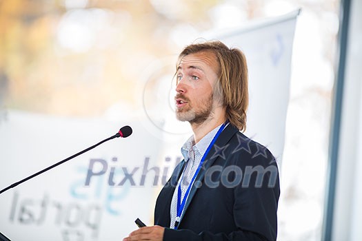 Handsome young man giving a speech at a conference Handsome young man giving a speech at a conference