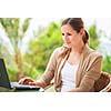 Portrait of a pretty young woman working on her computer on a terrace of her house