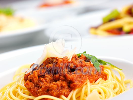 Italian spaghetti topped with bolognaise, or bolognese, sauce with tomatoes, meat and cheese on a plain white plate Italian spaghetti topped with bolognaise, or bolognese, sauce with tomatoes, meat and cheese on a plain white plate