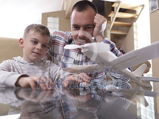 father and son assembling airplane toy at modern home living room indoor father and son assembling airplane toy at modern home living room indoor