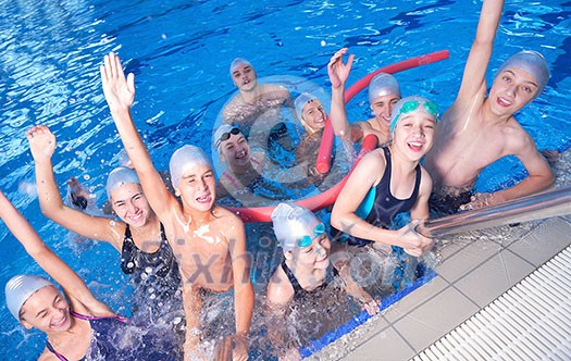 group of happy kids children   at swimming pool class  learning to swim