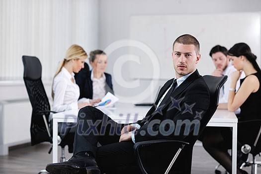 Portrait of a handsome young business man with people in background at office meeting Portrait of a handsome young business man with people in background at office meeting
