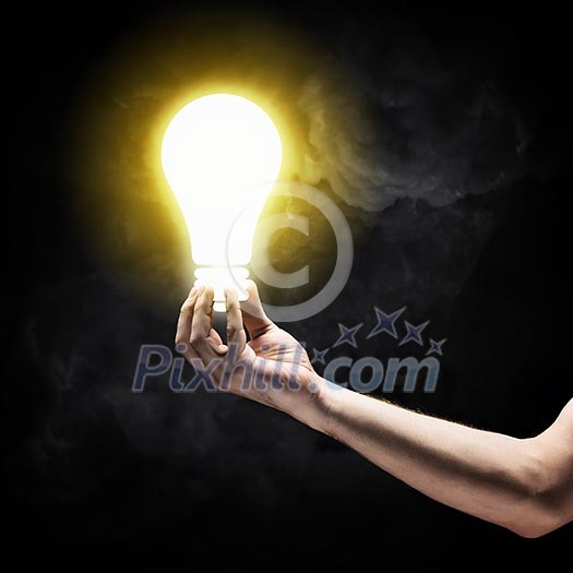Close up image of human hand holding electrical bulb in darkness Close up image of human hand holding electrical bulb in darkness