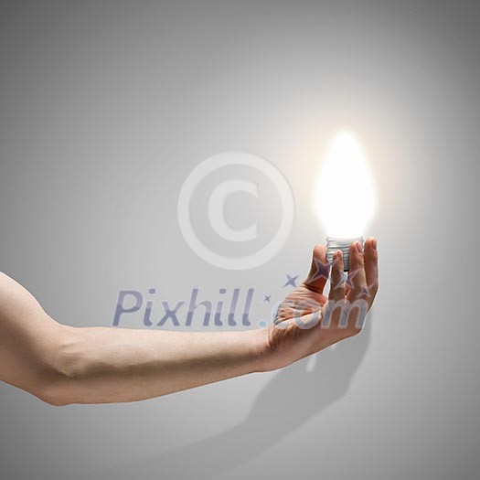 Close up image of human hand holding electrical bulb Close up image of human hand holding electrical bulb