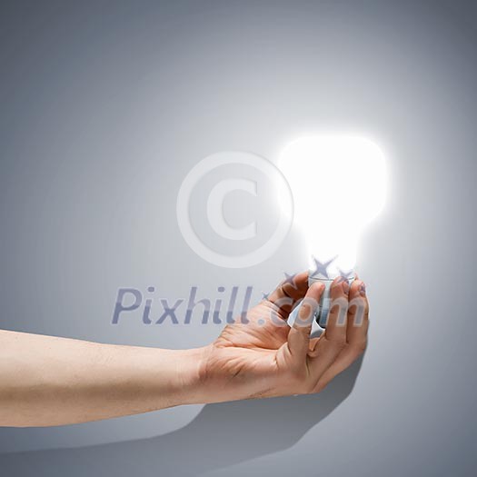 Close up image of human hand holding electrical bulb Close up image of human hand holding electrical bulb