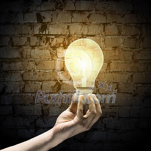 Close up image of human hand holding electrical bulb in darkness Close up image of human hand holding electrical bulb in darkness
