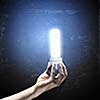Close up image of human hand holding electrical bulb in darkness