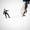 Young businessman balancing on rope controlled by male hand