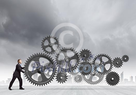 Young determined businessman making gear mechanism move Young determined businessman making gear mechanism move