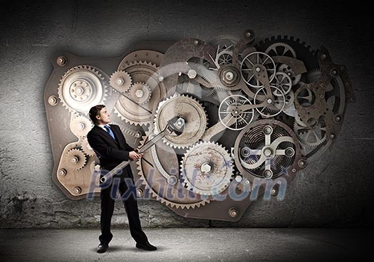Young businessman fixing gears mechanism with wrench Young businessman fixing gears mechanism with wrench