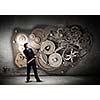 Young businessman fixing gears mechanism with wrench