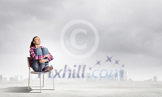 Young girl sitting in chair against city background Young girl sitting in chair against city background