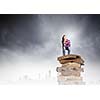 Young girl sitting on high pile of books