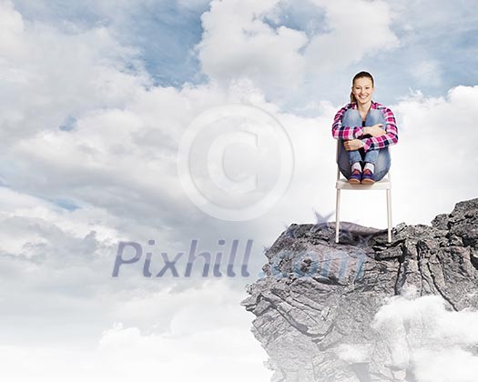 Young woman in casual sitting in chair on top of rock Young woman in casual sitting in chair on top of rock