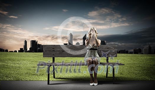 Young woman sitting on bench closing eyes with palms Young woman sitting on bench closing eyes with palms