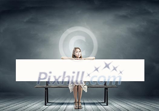 Young asian woman sitting on bench with blank banner Young asian woman sitting on bench with blank banner