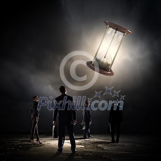 Conceptual image of business people looking at sandglass Conceptual image of business people looking at sandglass