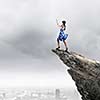 Young woman in blue dress standing on mountain edge