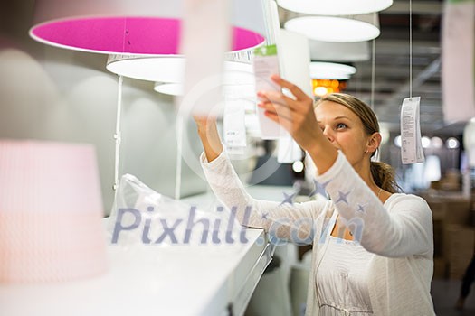 Pretty, young woman choosing the right light for her apartment in a modern home furnishings store (color toned image; shallow DOF) Pretty, young woman choosing the right light for her apartment in a modern home furnishings store (color toned image; shallow DOF)