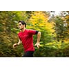 Young man running outdoors in a city park on a fall/autumn day (motion blurred image)