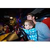 happy father and son playing driving wheel video game in playground theme park