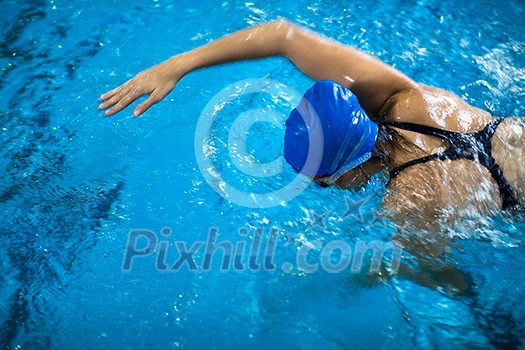 Female swimmer in an indoor swimming pool - doing crawl (shallow DOF) Female swimmer in an indoor swimming pool - doing crawl (shallow DOF)