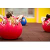 Group people in a pilates class at the gym - young woman with gymball at fitness training (shallow DOF, color toned image)