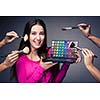 Cute make-up artist holding her vast palette of colors and hands with brushes around her (color toned image)