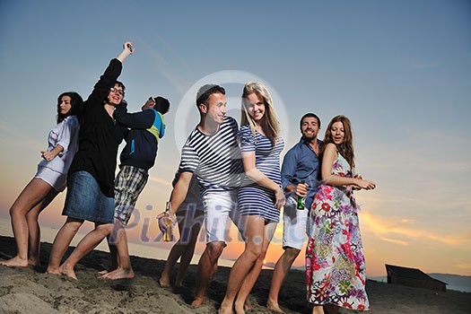 Group of young people enjoy summer party at the beach on beautiful sunset Group of young people enjoy summer party at the beach on beautiful sunset