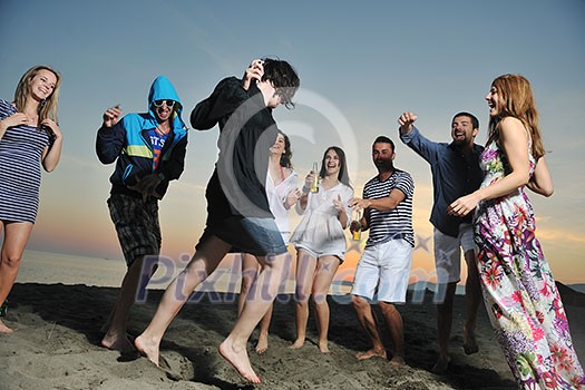 Group of young people enjoy summer party at the beach on beautiful sunset Group of young people enjoy summer party at the beach on beautiful sunset