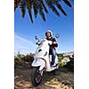 Portrait of happy young love couple on scooter enjoying themselves in a park at summer time