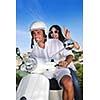 Portrait of happy young love couple on scooter enjoying themselves in a park at summer time
