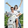 Portrait of happy young love couple on scooter enjoying themselves in a park at summer time