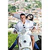 Portrait of happy young love couple on scooter enjoying themselves in a park at summer time