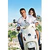 Portrait of happy young love couple on scooter enjoying themselves in a park at summer time